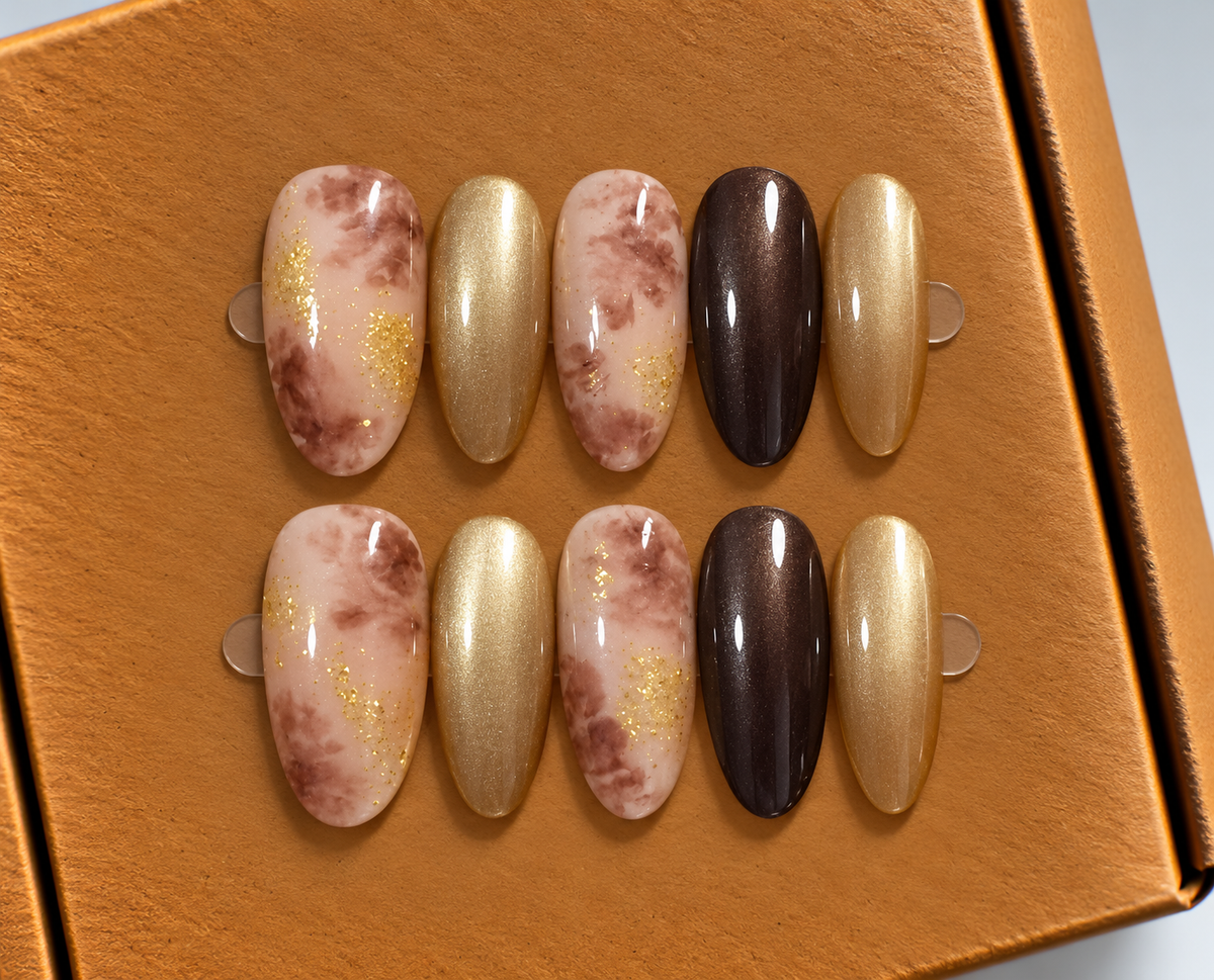 **Golden Mocha Marble Press-On Nails ✨🤎**  Elegant oval-shaped nails featuring soft brown marble patterns, shimmering champagne gold, and rich chocolate tones with delicate golden accents. A luxurious, glossy set for a sophisticated look.